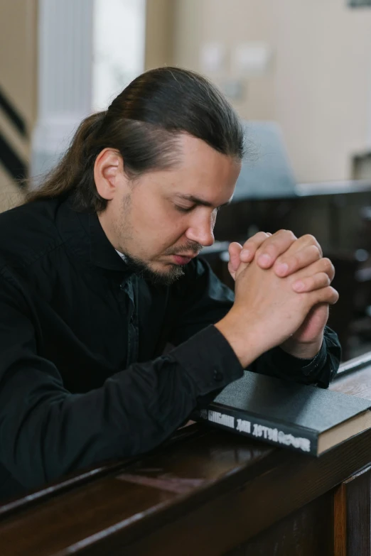 a man with his hands folded with his face up on a desk