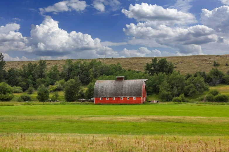 the barn sits on a hill near the green field