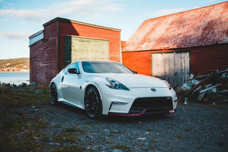 a white nissan is sitting next to the barn