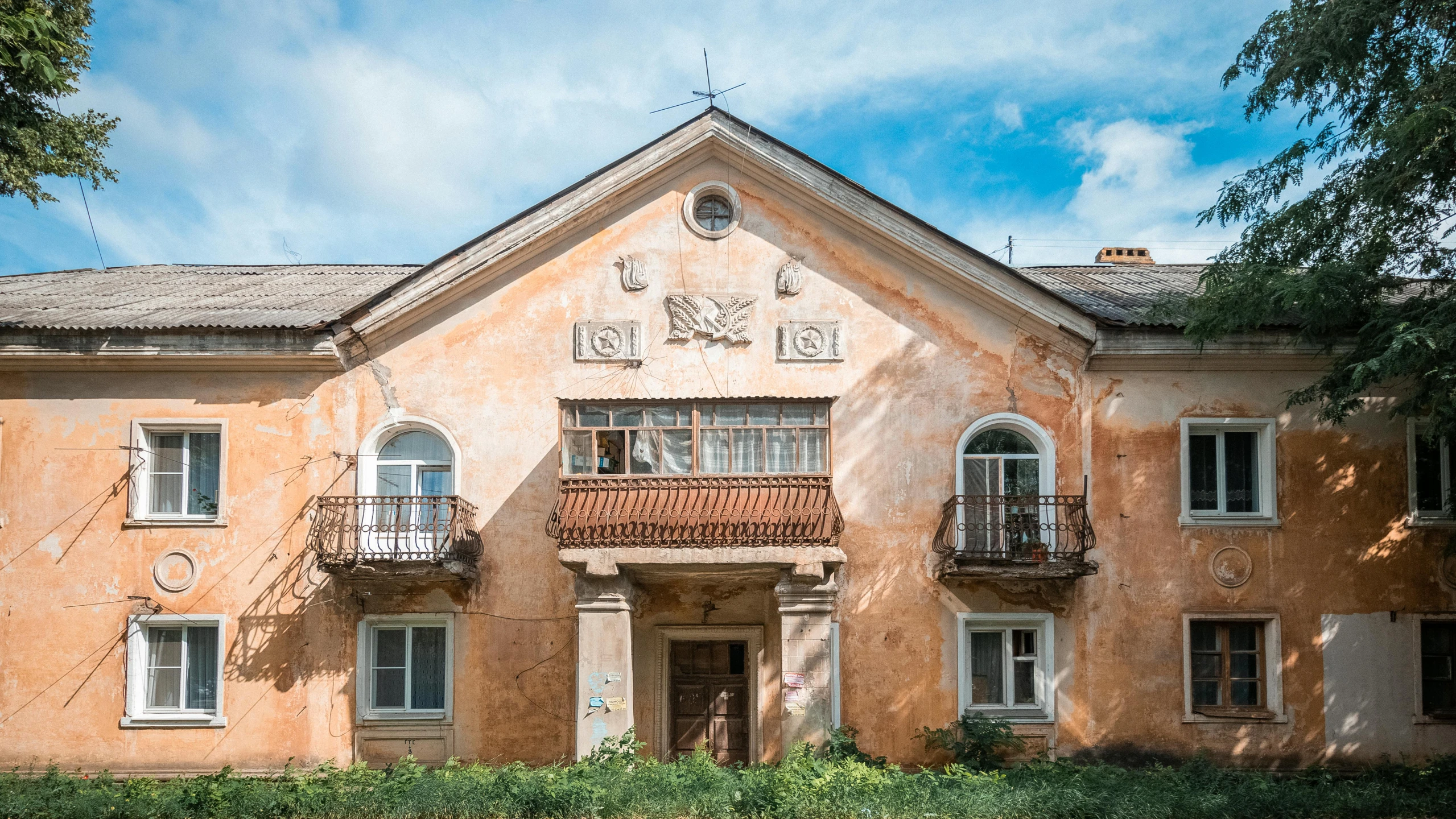 a beautiful old building with a tree and shrubbery surrounding it