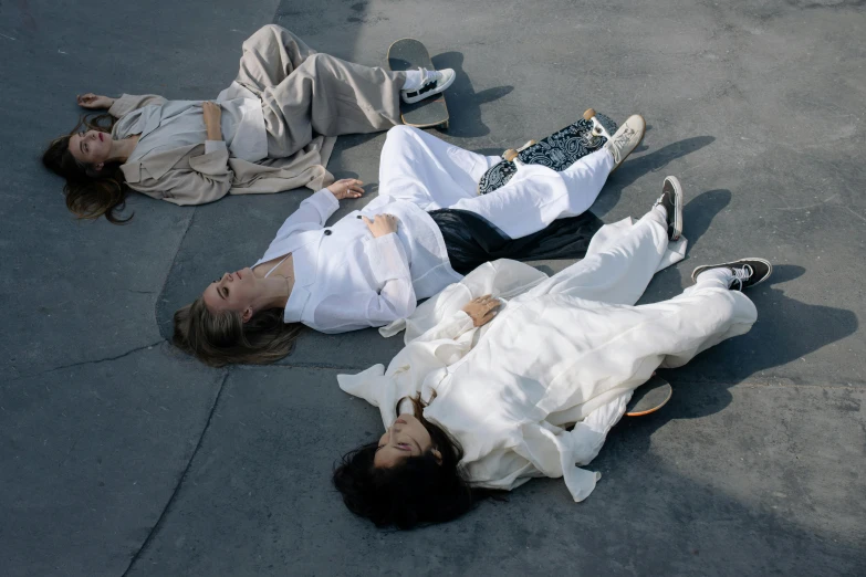 three people laying on the sidewalk with their arms around each other