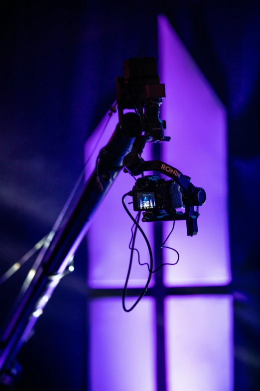 a camera and microphone connected to a tripod in front of purple light