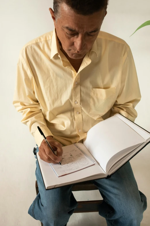 a man with a pen sitting on a chair in front of a book