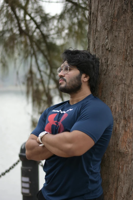 a man leaning on a tree looking at the water