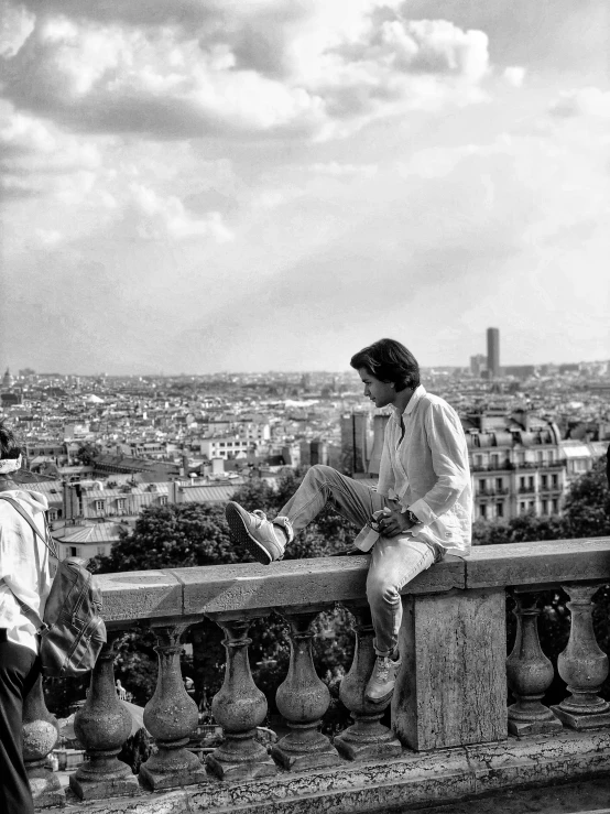 black and white po of people sitting on a balcony with a city in the background