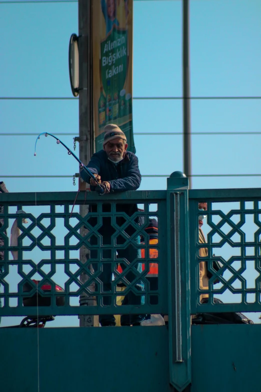 a man holding two fishing rods over a metal railing