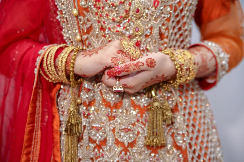 the arm and hands of a person wearing a colorful dress and jewelry