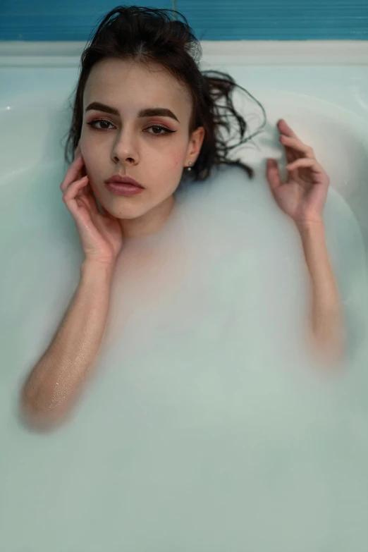 young woman laying in large bubbley water looking to the side