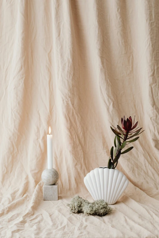 a white candle sitting in front of a vase of flowers