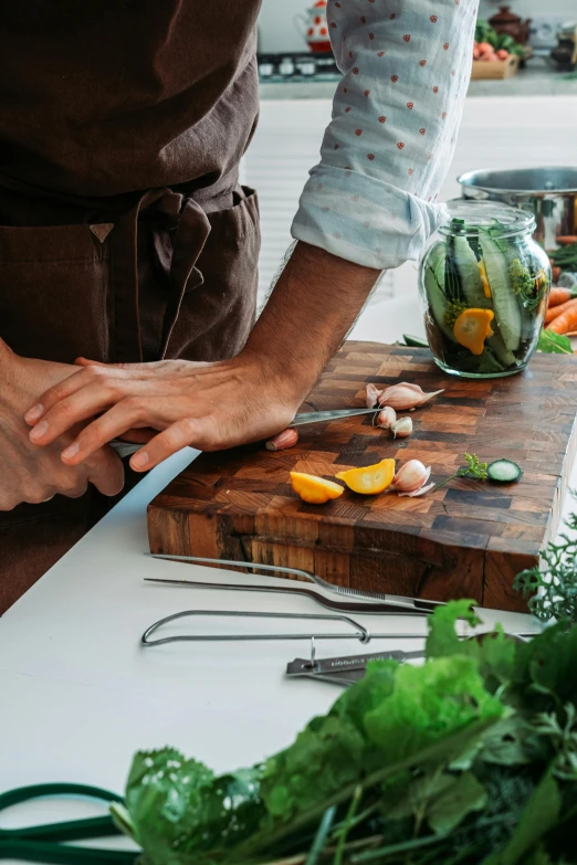 someone with a knife on top of a  board next to greens