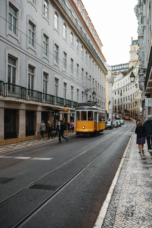 several people walking on the sidewalk in front of a train