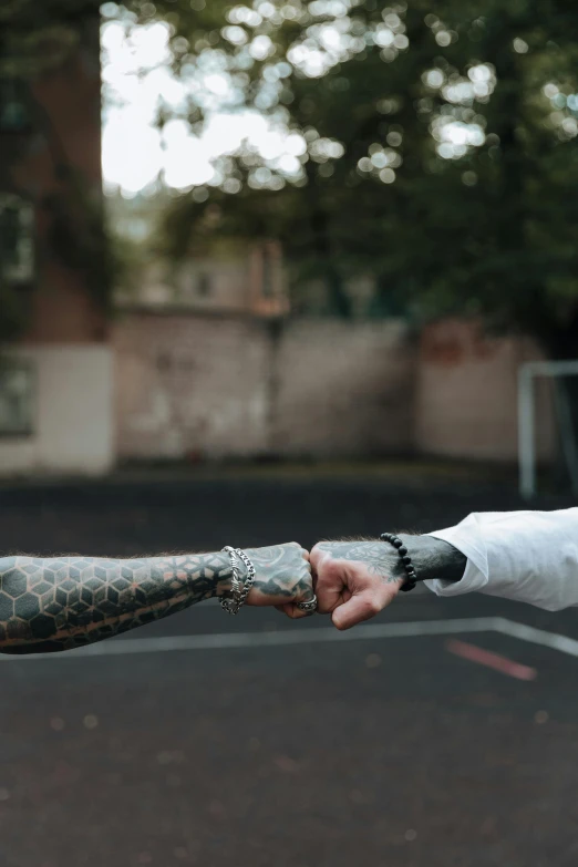 a person with tattoos is standing in a parking lot and has her hand extended out towards the guy's arm