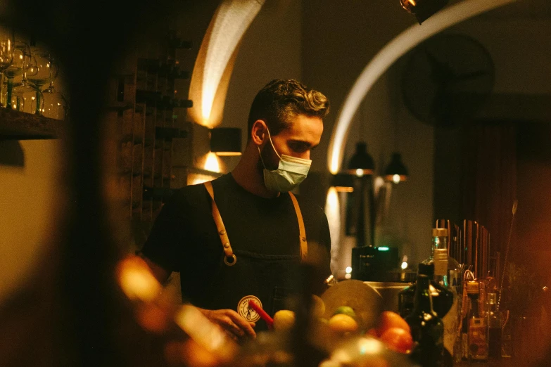 a man wearing a face mask looking at bottles in a bar