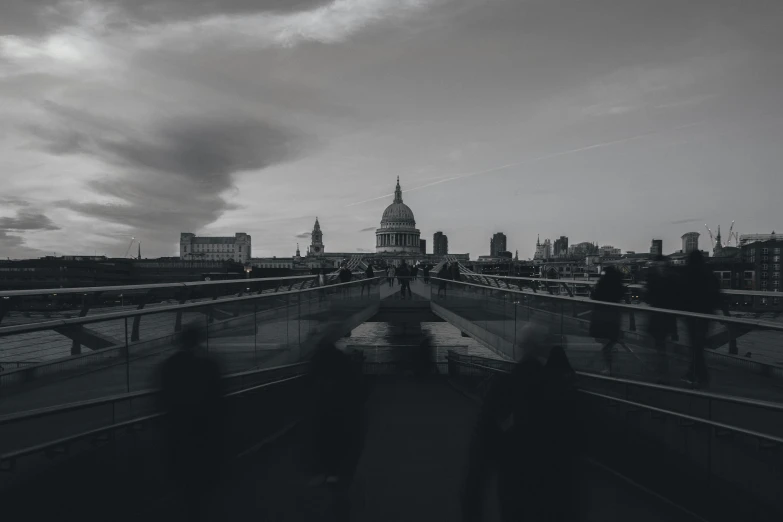 black and white pograph of bridge overlooking building and a cloudy sky