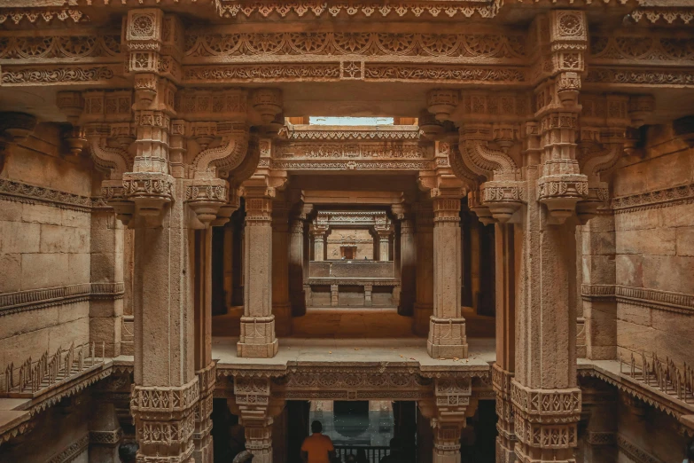 large white and beige building with pillars with people walking underneath