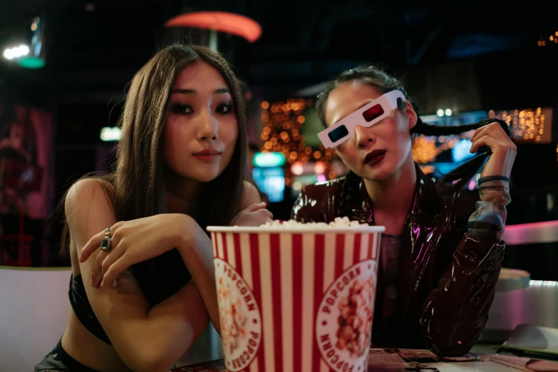 a man and woman in 3d glasses in front of a popcorn bucket