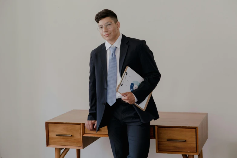 a man in a suit with glasses is standing by a desk