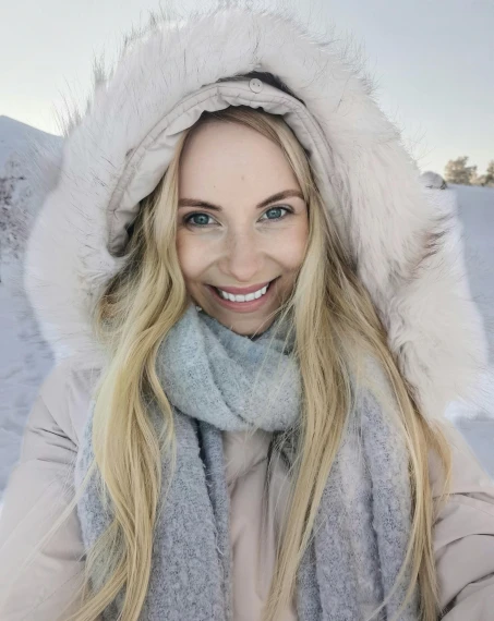 a beautiful blonde woman with blue eyes wearing a scarf and hat