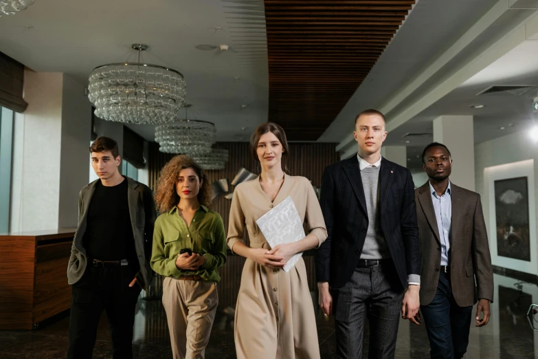 four people walk down a hall holding papers