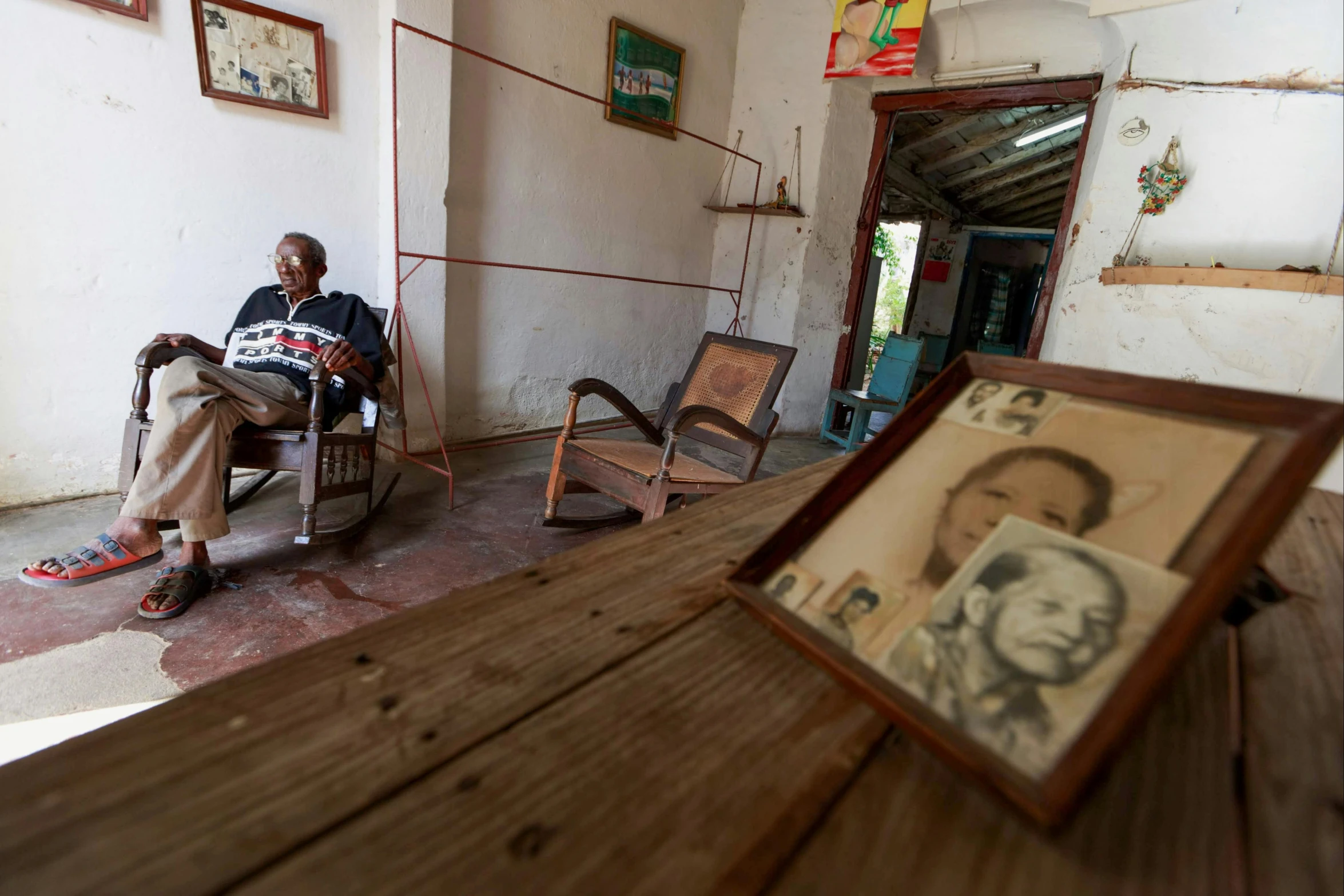 man sitting in chair with po in frame and small framed picture on the floor