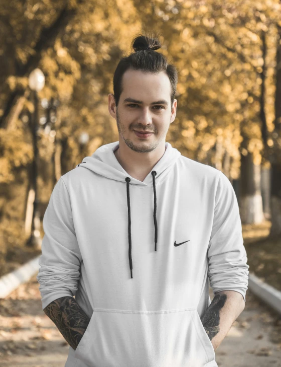 a man in a white hoodie stands on a road