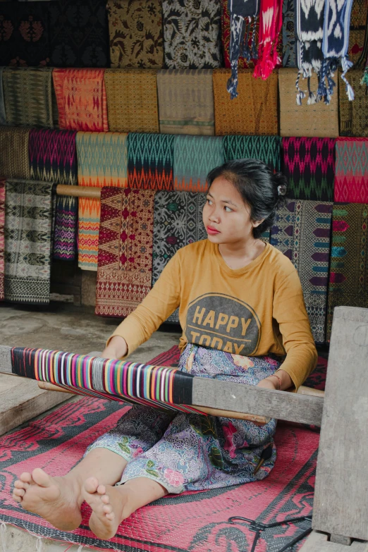 a woman sits on a colorful rug in front of several colorful items