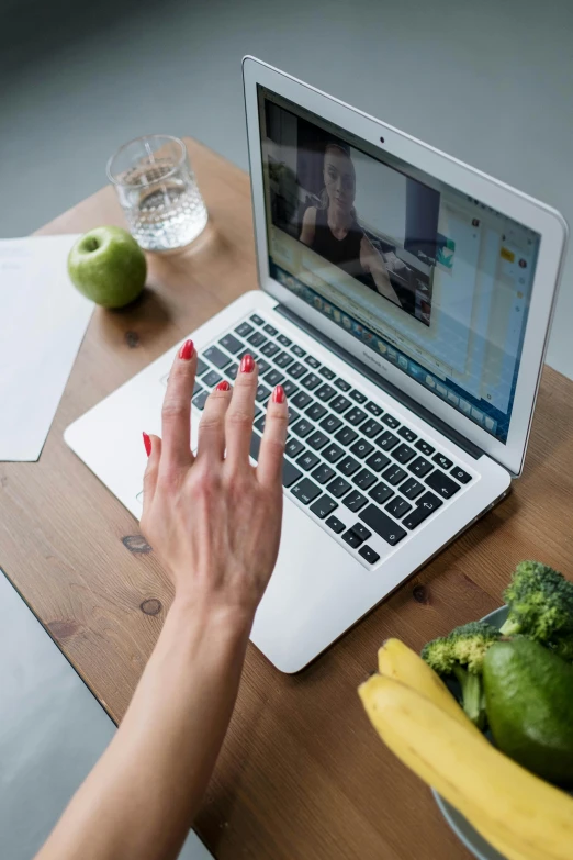 a woman using a laptop computer with some food on the table