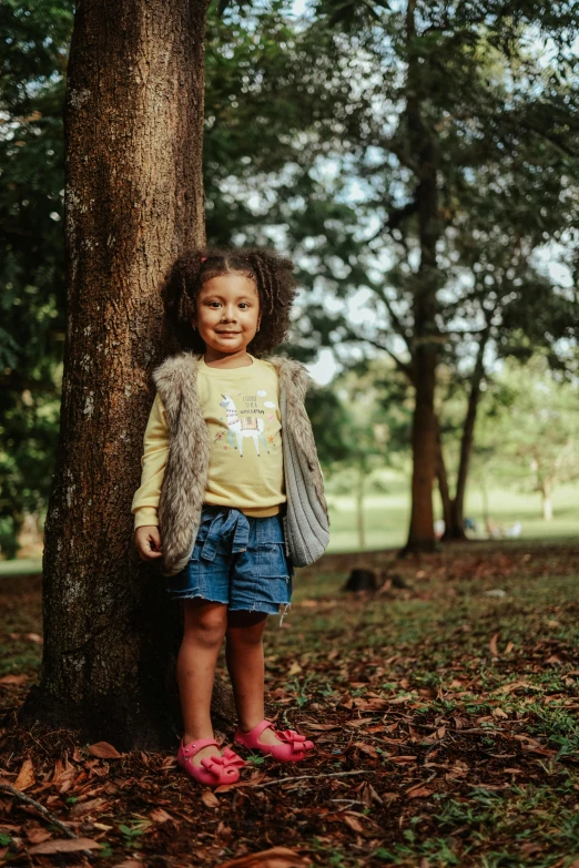 a child standing next to a tree wearing pink shoes