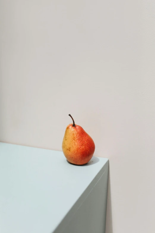 a pear on top of a white table next to a wall