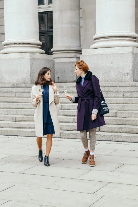 two women in coats talking on the steps of building