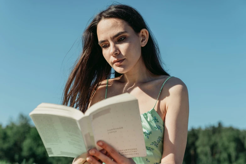 a woman reads a book while standing in a field