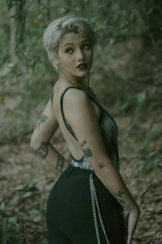 a woman with short hair and piercings poses in the woods