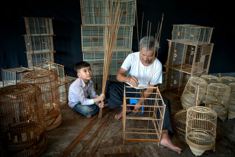 two people are working on wooden birds cages