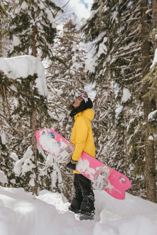 a girl is holding her snowboard while standing in the snow