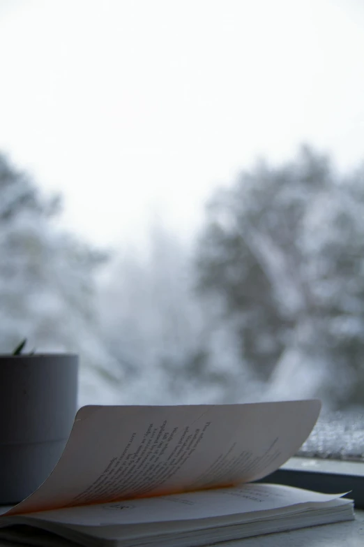 an open book and a cup sitting by a window