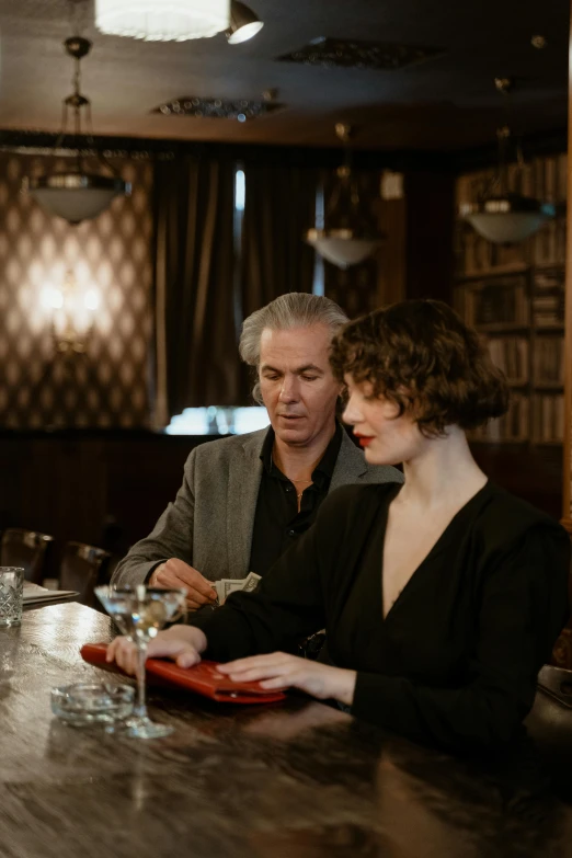 two people sitting at a table with a bottle of wine and a glass