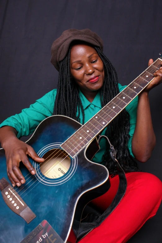 woman sitting holding up a guitar and posing for a picture