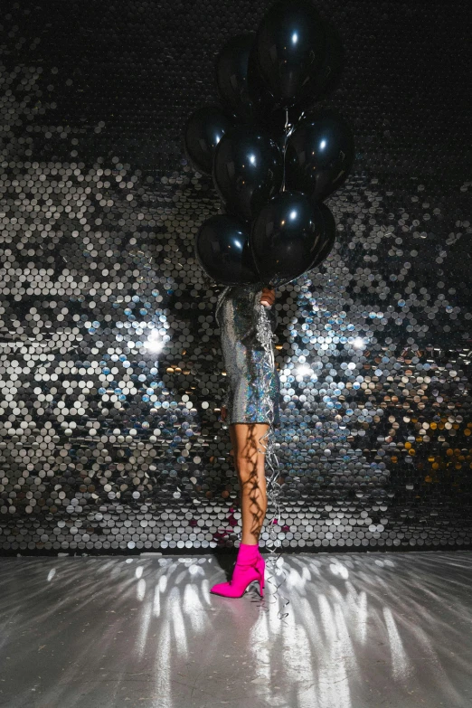 the woman has balloons in her hand as she walks through the room