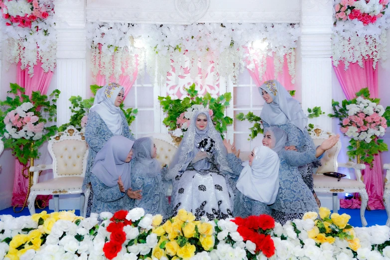 two women and a child in dresses sit on the bed of flowers