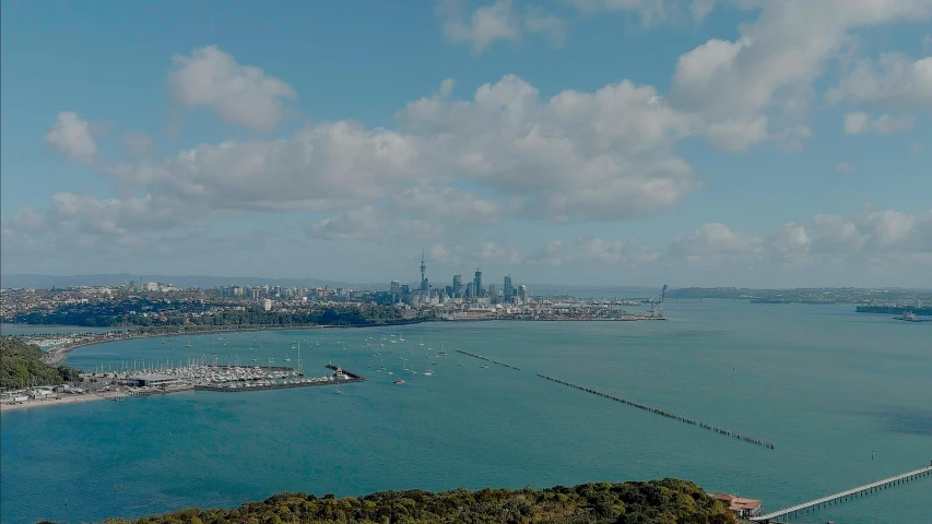 a view from the air shows boats on the water, and a city on the horizon