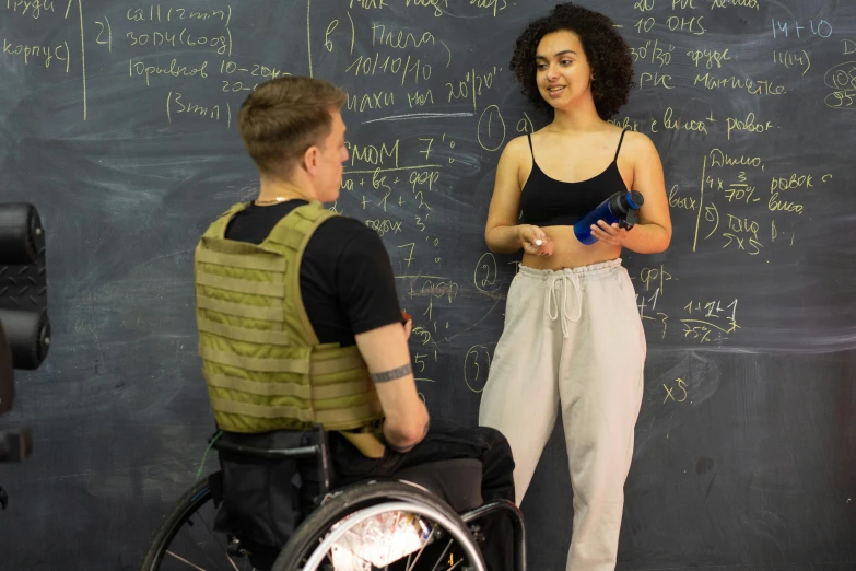 two people in wheelchairs near a chalkboard with writing