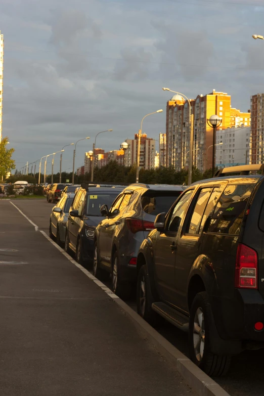 rows of parked cars in parking lot with large city skyline in background