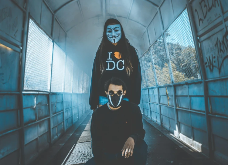 man and woman in white face masks crouching against each other