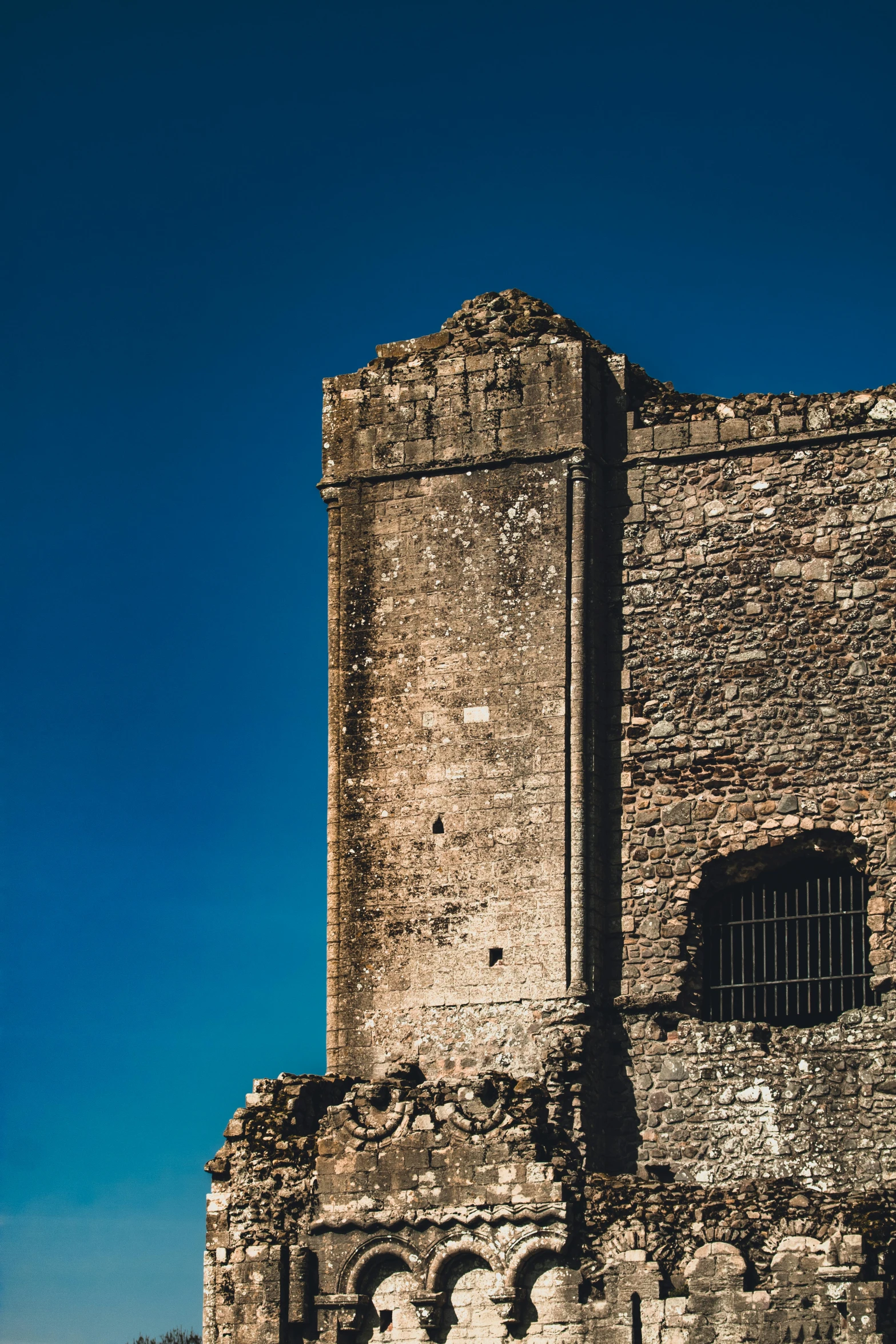 a tall stone building next to a tall fence