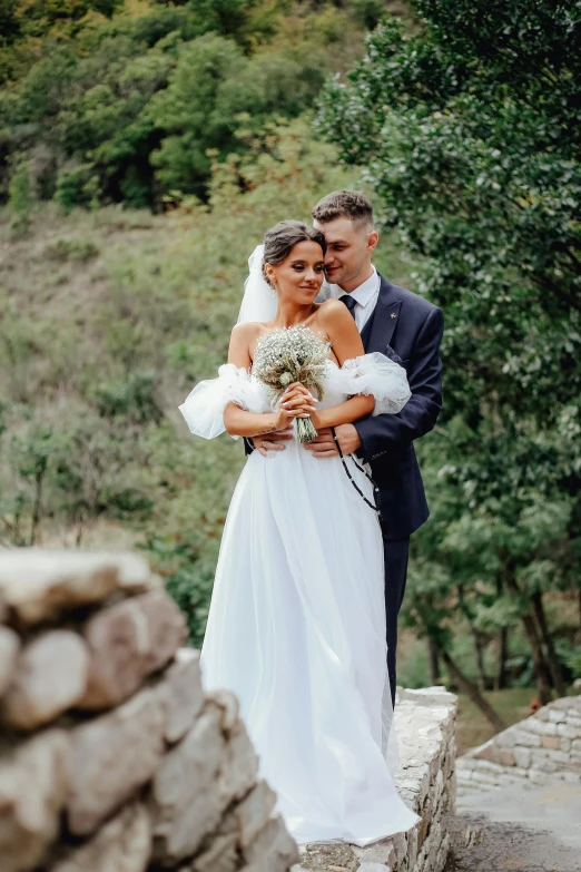 a newly married couple hugging on a bridge