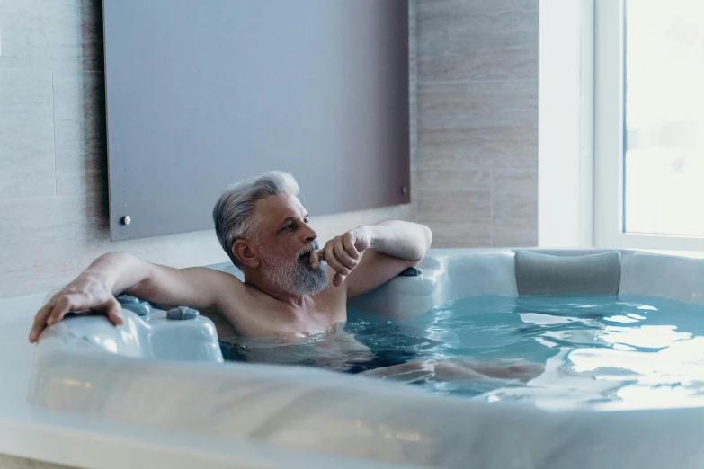 man lying in an indoor swimming tub with an ice box