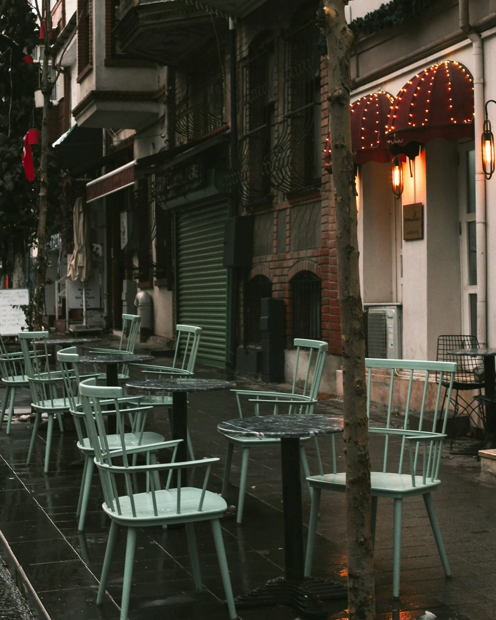 a sidewalk lined with green outdoor patio furniture