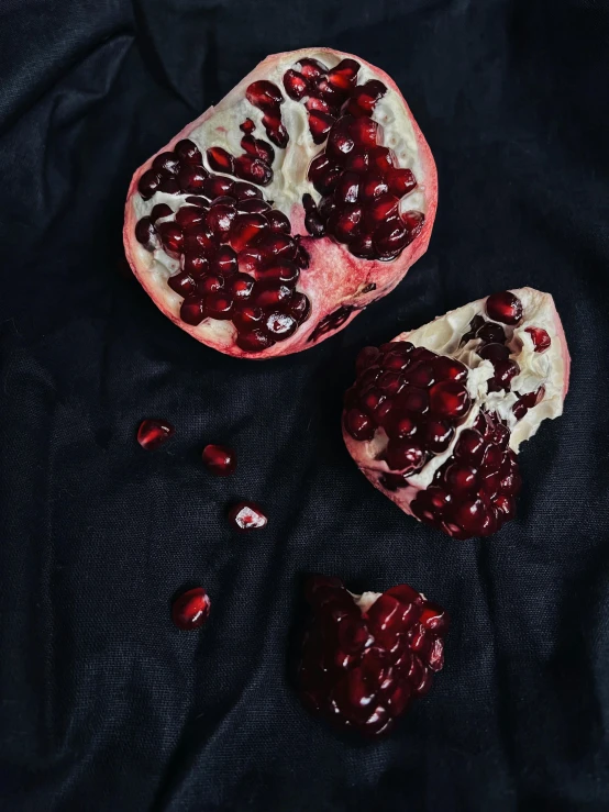 three pomegranates cut into in half on a cloth
