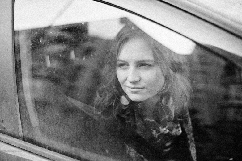 a woman sitting inside a car looking out the window