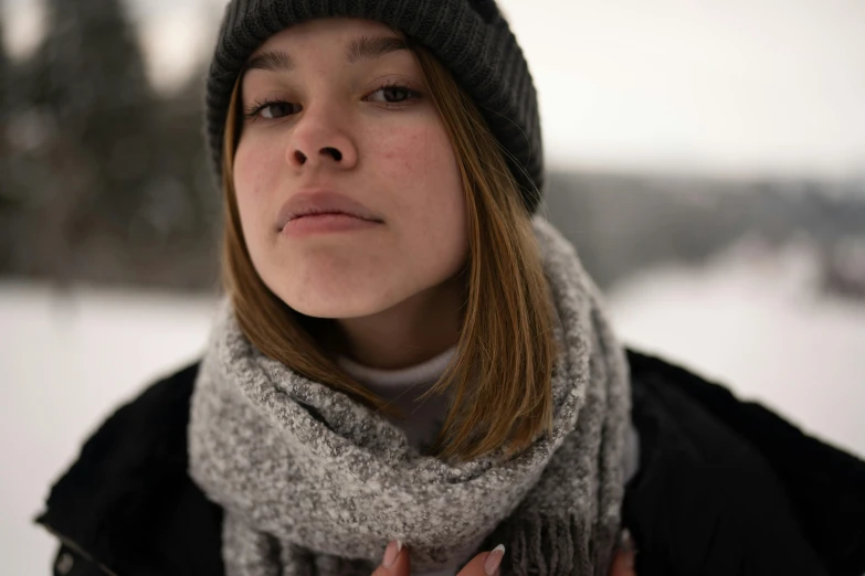 the woman is wearing a hat and scarf with her hands under her chin